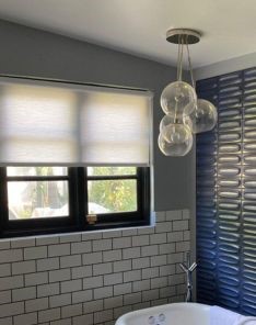 Modern bathroom in San Marcos featuring closed sheer roller shades for windows that filter natural light and ensure privacy.