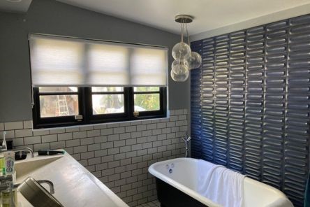 Bathroom window in San Marcos with custom sheer window shades half open, allowing sunlight while maintaining a cozy atmosphere.